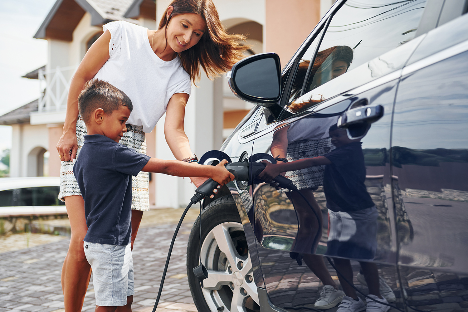 Caregiver and child charging an electric vehicle.
