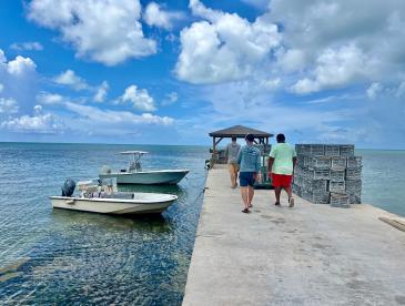 Two small vessels next to a pier, against a backdrop of open water.