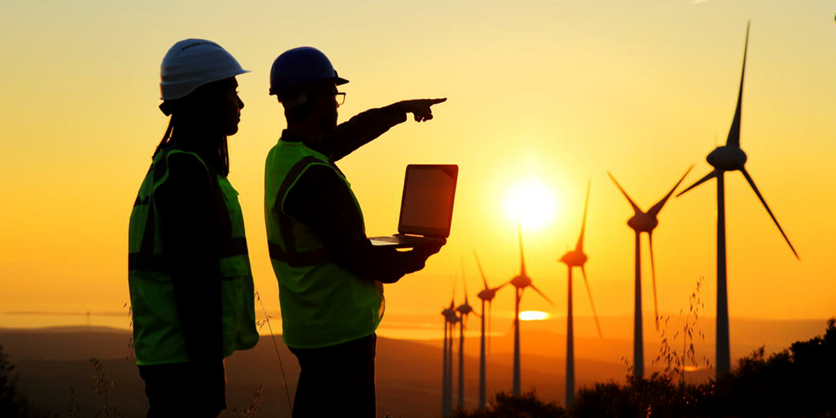 Workers in hard hats, with a row of windmills in the background.