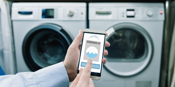 man operating smart washer and dryer with smartphone