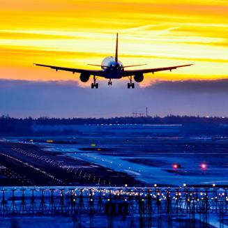 Plane above runway at sunrise or sunset