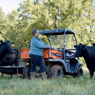 Beverly Bowen, who runs a small-scale farm in North Carolina, stands need black cattle and an orange 4x4 vehicle..