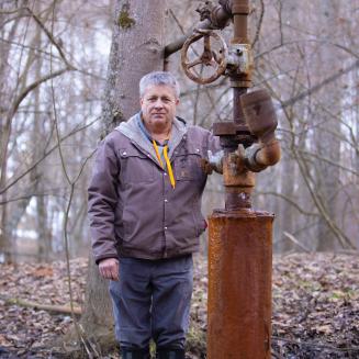 Farmer William Suan with leaking orphan well on his property