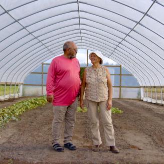 Fifth-generation farmers Millard and Connie Locklear stand in a plastic tunnel similar to the one in which they grow their tomatoes