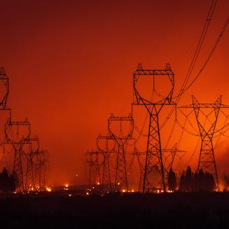 Transmission towers silhouetted by wildfire