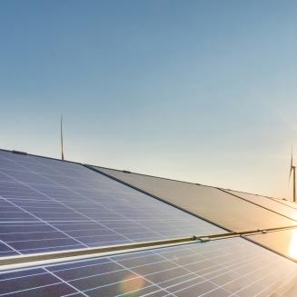 Windmills stand in the background, with solar panels in the foreground.