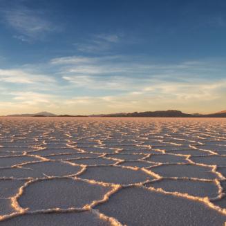 A wide expanse of salt flats with mountains in the distant background