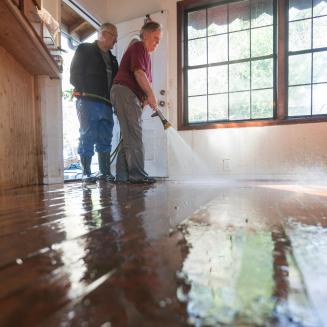 Two people power washing floors after flood damage