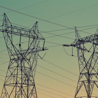 Electricity transmission towers silhouetted against a green-blue sky