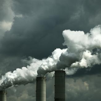 Smokestacks releasing emissions on a cloudy day.