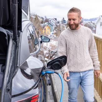 A man charges an electric car at a charging station in Norway.