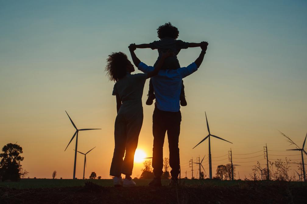 Family staring at field of wind turbines at sunset