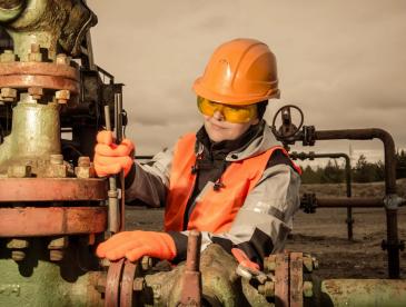 Female oil and gas worker working on machinery