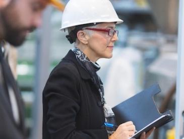 Woman wearing hard hat and business suit in a factory
